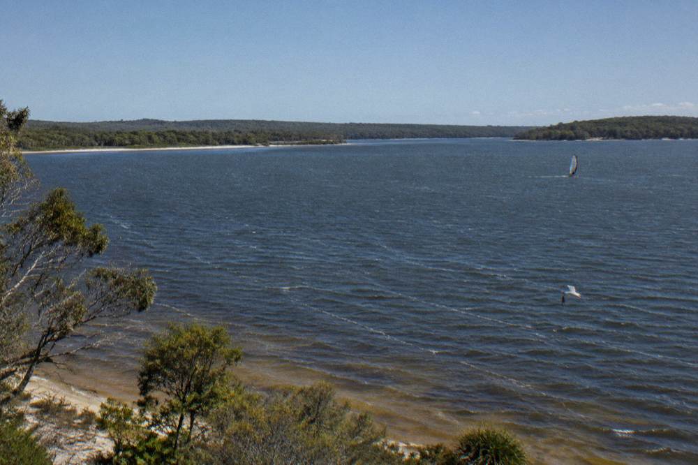 Wide calm lake with dark water and tree lined shores under a clear sky