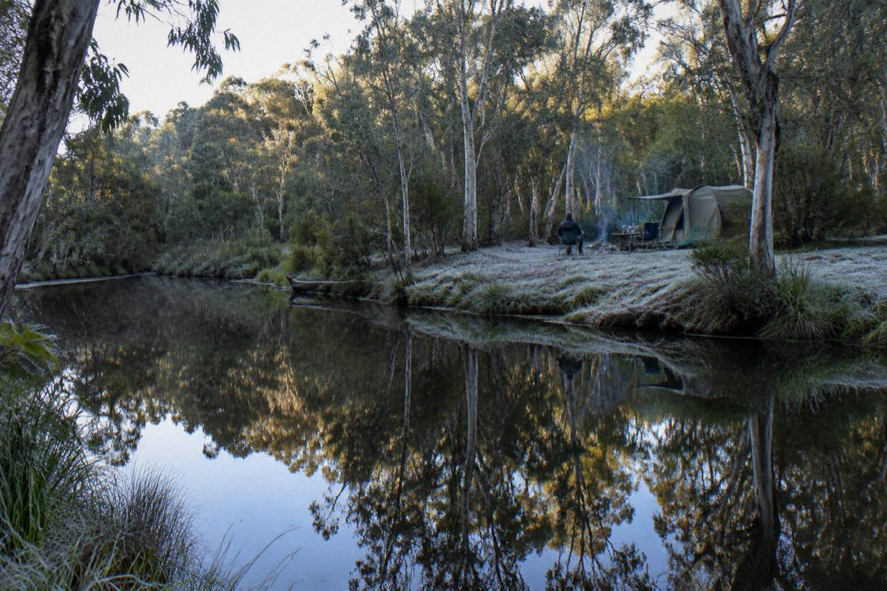 Dark calm river reflecting paperbark trees along a narrow waterway