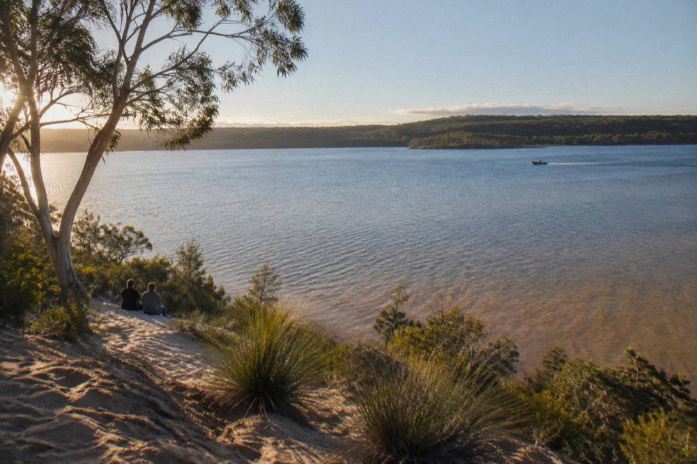 Wide shallow lake with forested shoreline in the background under morning light