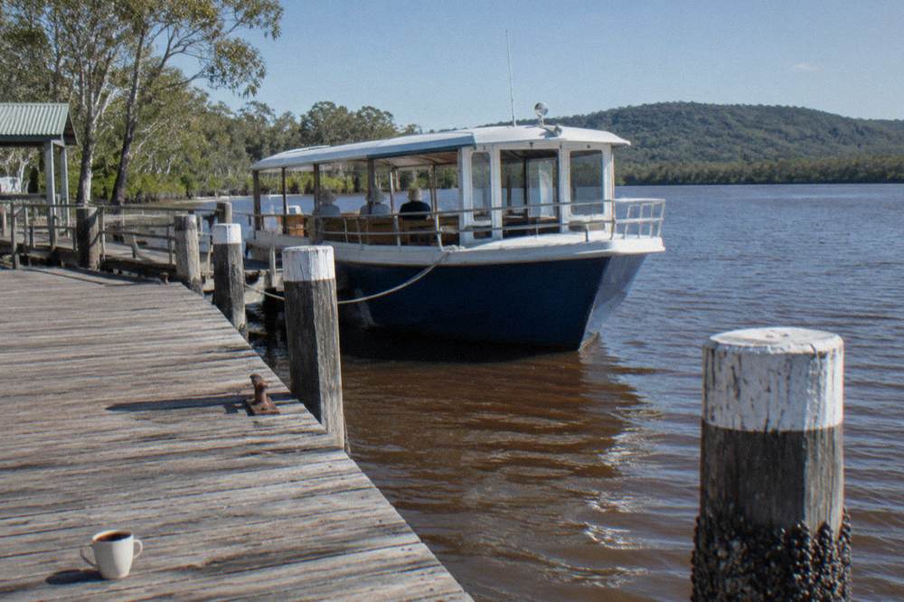 A cruise boat moored at a wooden jetty on a tannin-brown lake