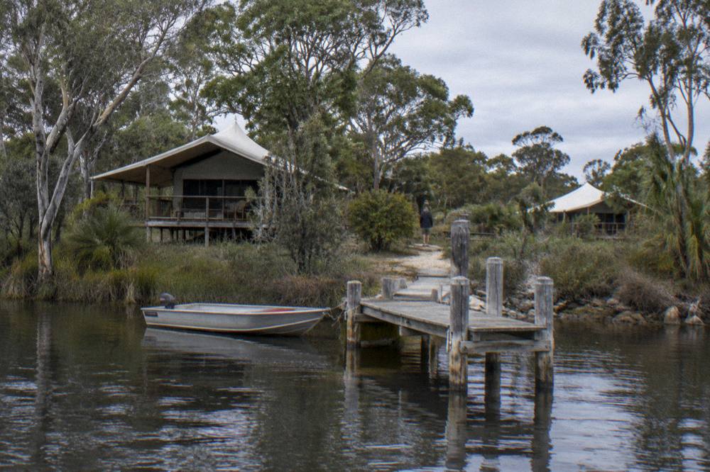 A small boat moored beside a wooden jetty on a calm dark lake at midday