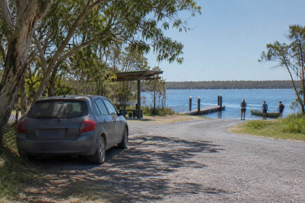 Grass-edged car park beside a jetty at Elanda Point on Lake Cootharaba