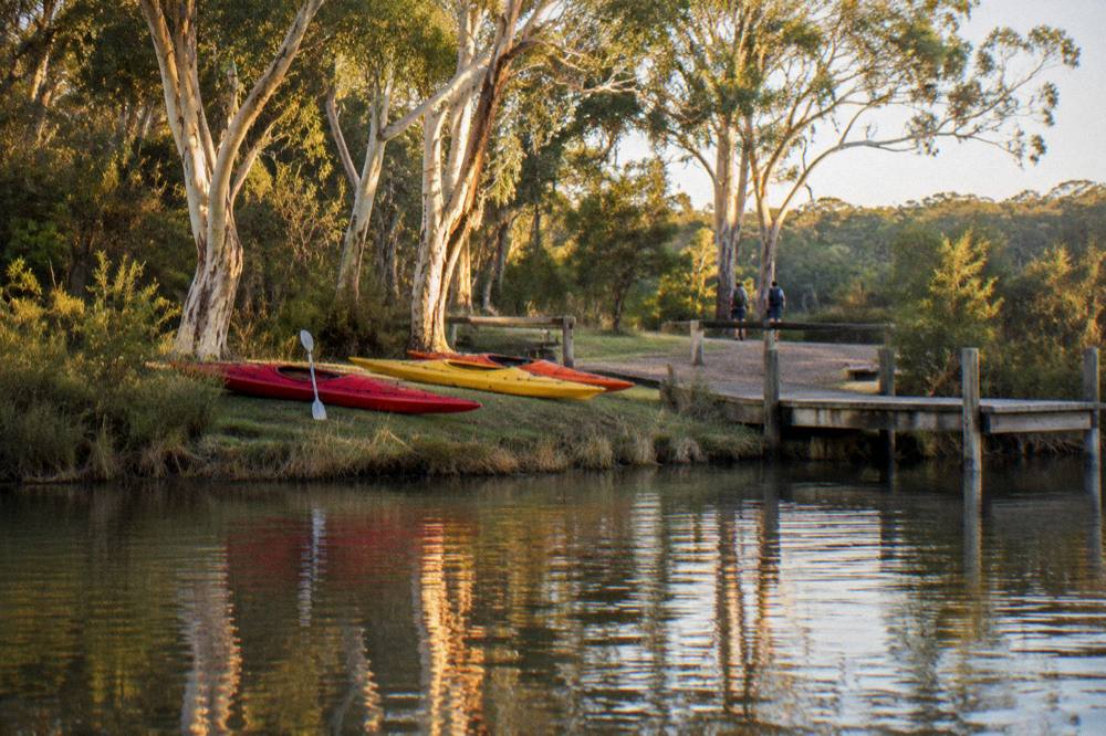 Kayaks resting on a grassy bank beside a jetty at Elanda Point