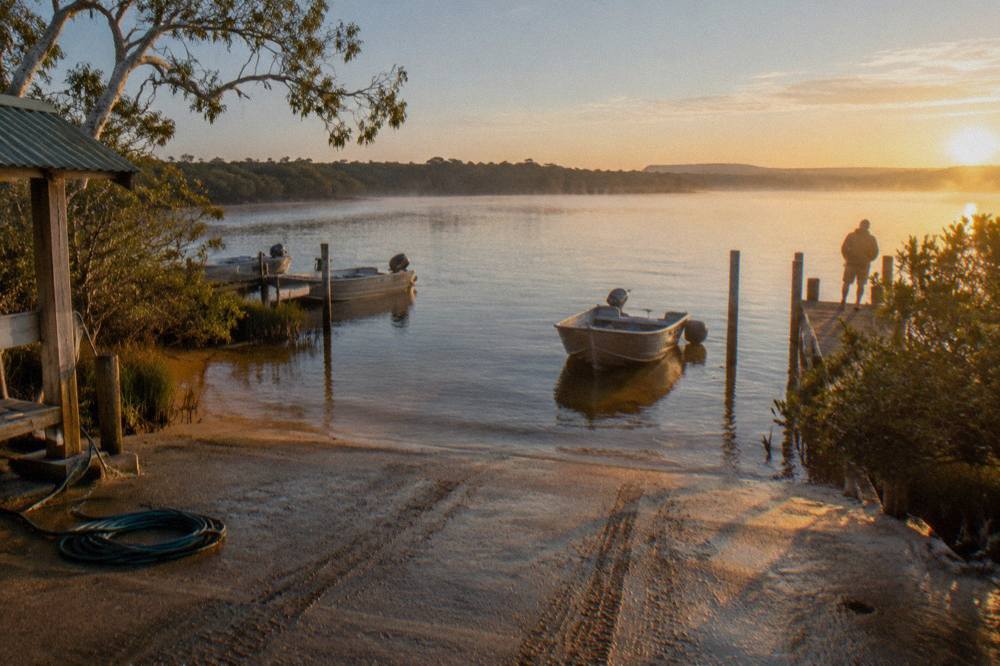Calm open lake water at dawn with distant tree-lined shoreline
