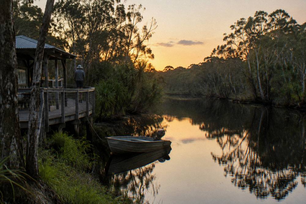 Late afternoon calm on a narrow tannin river with a full reflection of the treeline