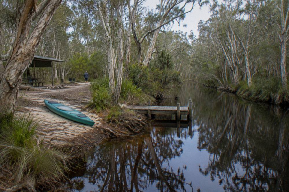 Still morning river with mirror reflections of trees along a narrow channel